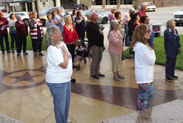 Several locals join Nadine Cowley (center, foreground) and Marilyn Petrick (donned in the American flag) during the national anthem May 4 during the National Day of Prayer service in Burnet at the County Courthouse. Raymond V. Whelan/Bulletin