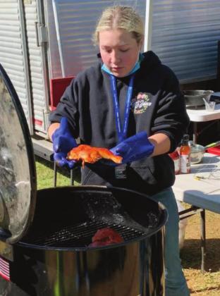 Burnet FFA BBQ team member Jordon Erickson prepares to place chicken into a drum smoker at the HS BBQ Inc. state championship, held at the John L. Kuykendall Event Center in Llano. Contributed