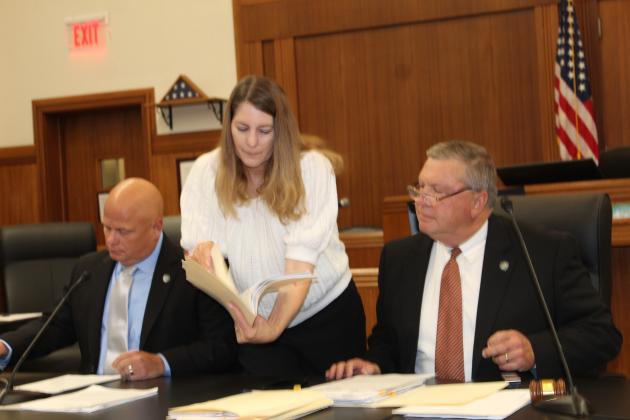 Burnet County Judge James Oakley (right) receives documents from County Auditor Karin Smith before the start of the Sept. 12 meeting. Precinct 2 Commissioner Damon Beierle sits next to the auditor.  Raymond V. Whelan/Bulletin