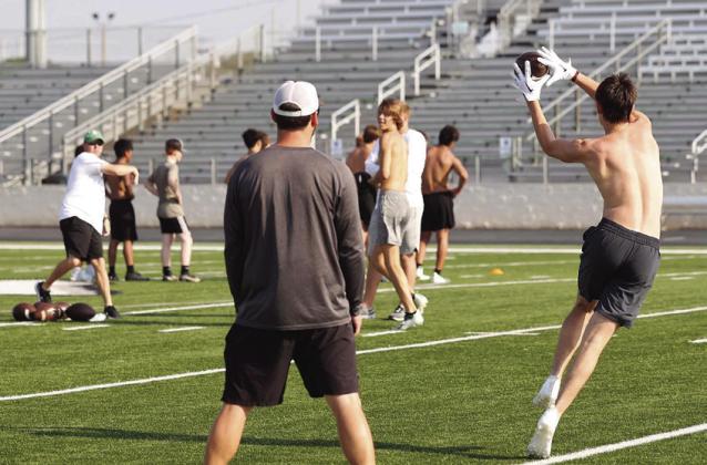 Bulldog Andrew Milum catches a pass from Burnet coach Trevor Couch. The Bulldogs are staying in shape and conditioning this summer by utilizing the summer workout program.