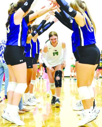 Lady Bulldog Lauren Howton smiles as she runs through a tunnel made by Lampasas’ players in a good show of sportsmanship during introductions Friday night.