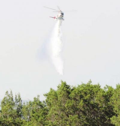 A Texas A&M Forest Service Type 1 helicopter drops water picked up from Lake LBJ onto a wildfire in the Blue Lake subdivision Thursday, Aug. 13. A helicopter from Star Flight and three single-engine air tankers using fire retardant were also put into action to help suppress the fire. Lew K. Cohn/Burnet Bulletin