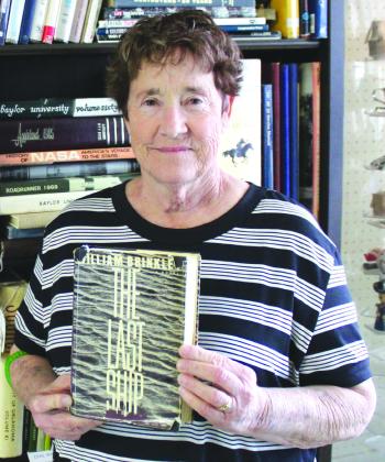Burnet Antique Mall Clerk Paula Podhajsky holds one first edition copy of the gripping, first edition novel “The Last Ship” by William Brinkley, before stacks of shelves filled with several other valuable volumes offered by John and Carol Will, including The Yale Shakespeare Complete Works and writings by Rudyard Kipling. Photos by Raymond V. Whelan/Bulletin